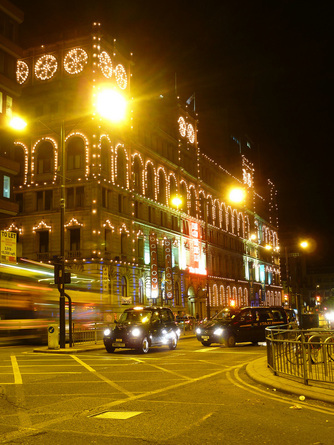 Manchester city lights with a passing taxi.